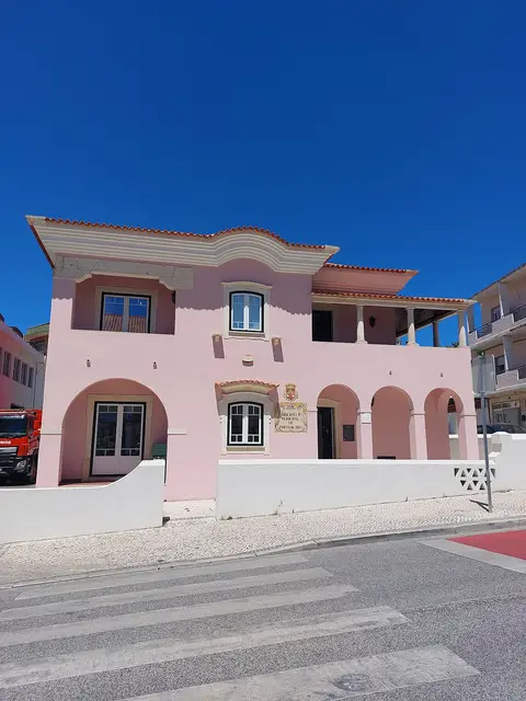 Edifício rosa da Biblioteca Municipal de Porto de Mós, antiga Casa dos Magistrados, com céu azul