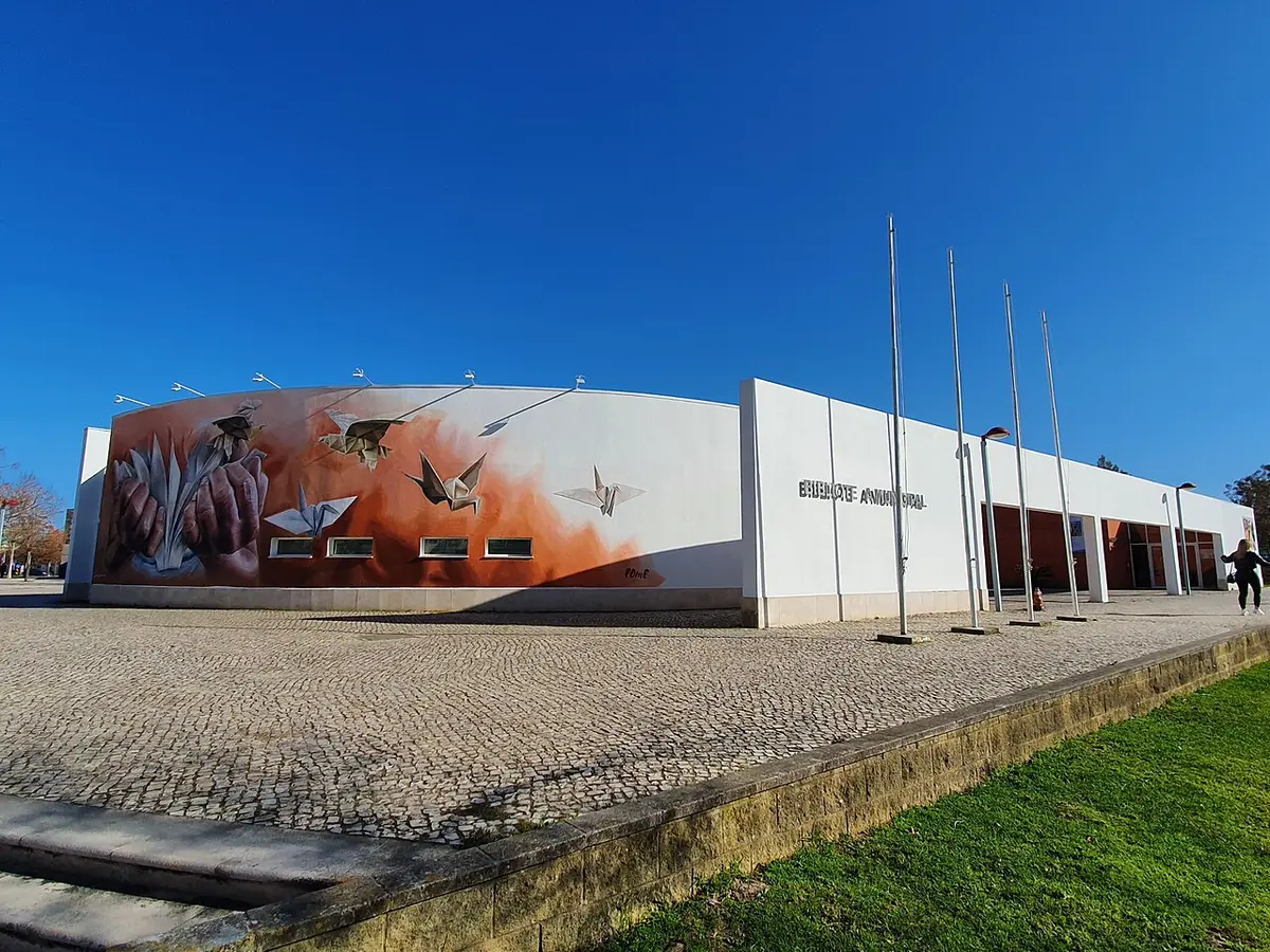 Exterior da Biblioteca Municipal de Pinhal Novo com mural de aves e origami e mastros de bandeiras