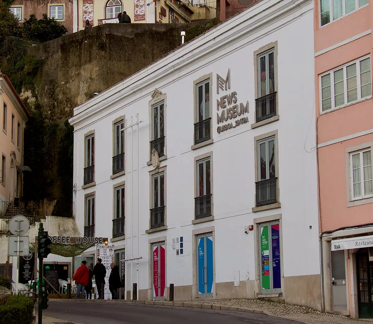 Fachada branca do NewsMuseum em Sintra, com letreiro e portas coloridas ao nível da rua