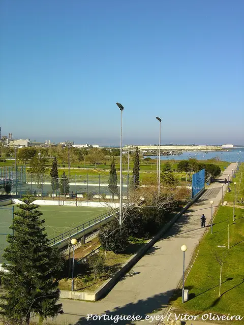 Vista do parque municipal com campos desportivos, passeio arborizado e rio ao fundo