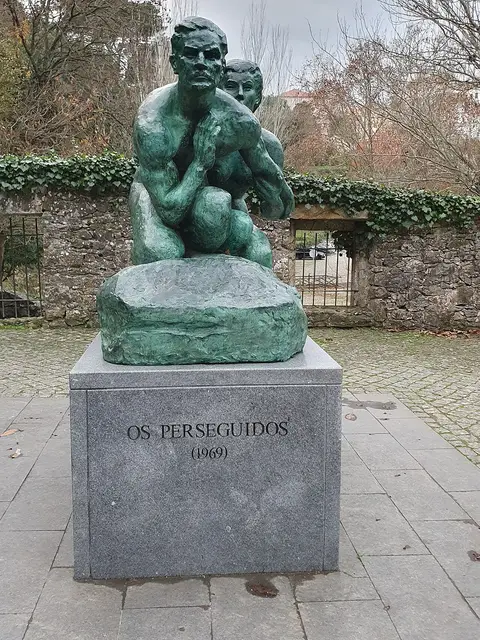 Escultura em bronze "Os Perseguidos" (1969) sobre pedestal de pedra, ao ar livre