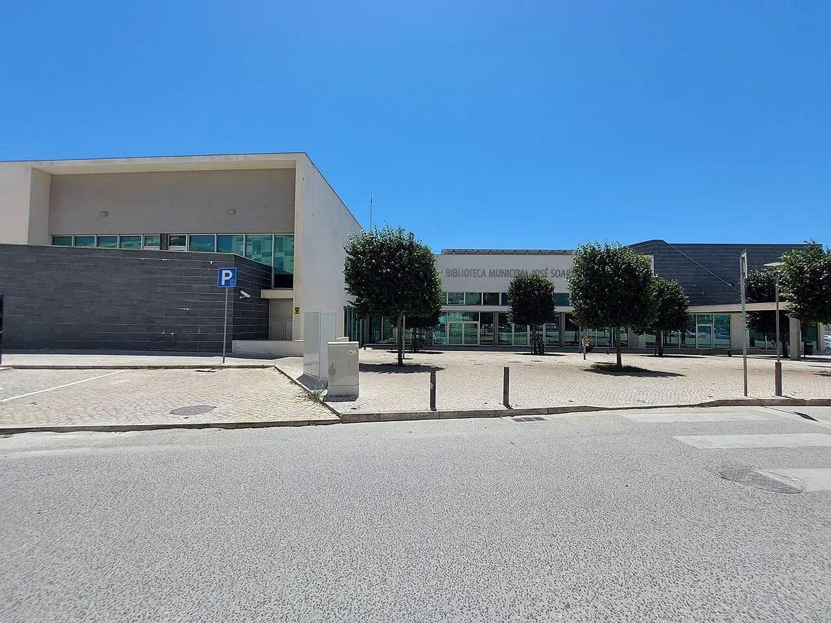 Exterior da Biblioteca Municipal da Nazaré, edifício moderno com árvores e praça pavimentada
