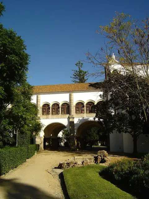 Palácio de Dom Manuel em Évora, com galeria de arcos geminados, rodeado pelo jardim público.