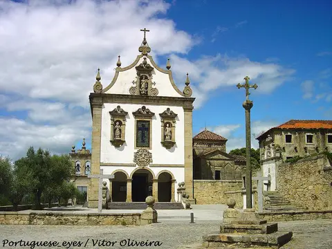 Fachada branca barroca da igreja de São Francisco com cruzeiro de pedra e capela de São Frutuoso ao lado