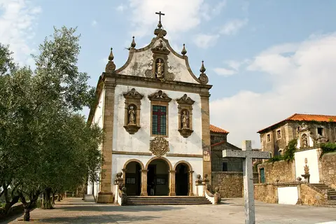 Fachada barroca da igreja do Convento de São Francisco, com cruzeiro de pedra e oliveira em primeiro plano