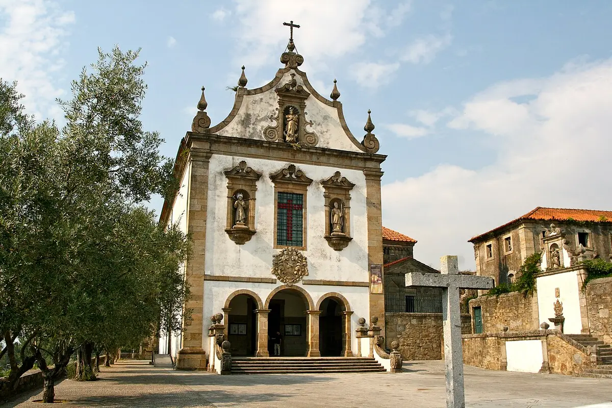Fachada barroca da igreja do Convento de São Francisco, com cruzeiro de pedra e oliveira em primeiro plano
