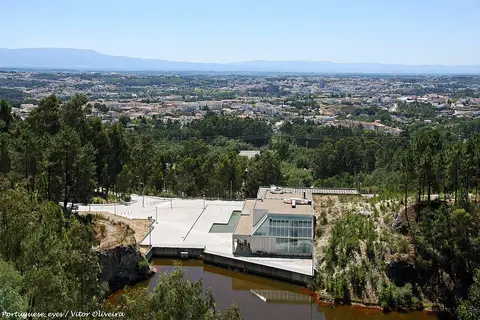 Edifício do Museu do Quartzo junto a uma antiga pedreira alagada, com a cidade de Viseu ao fundo