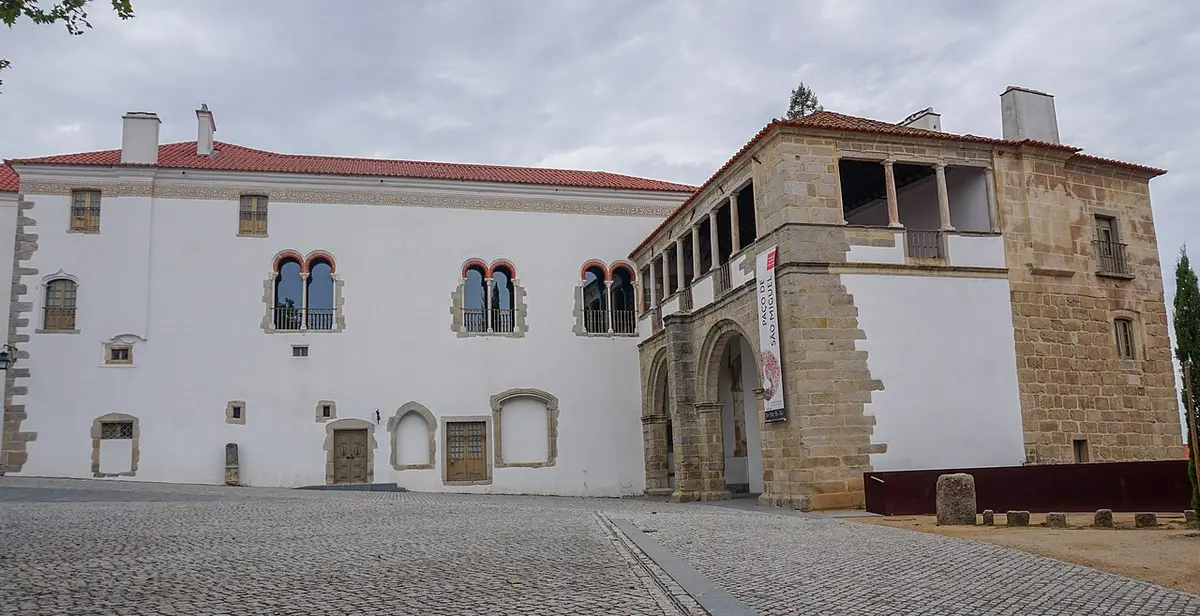 Fachada branca do Palácio dos Condes de Basto em Évora, com janelas geminadas e torre em pedra.