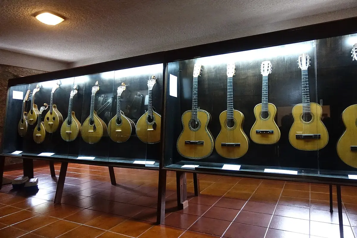 Vitrina de museu com guitarras e cavaquinhos portugueses expostos em parede escura
