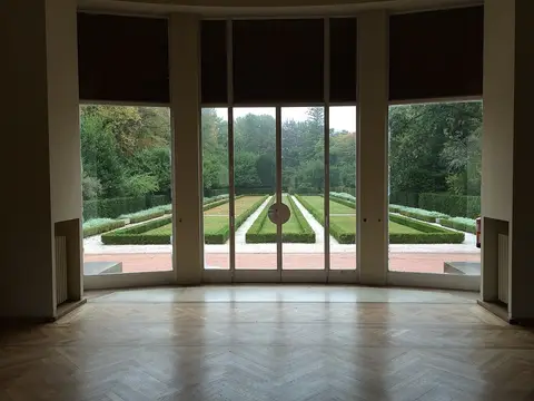 Sala da Casa de Serralves com janela envidraçada sobre os jardins geométricos