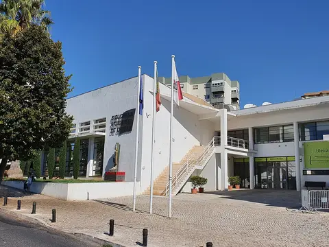 Edifício branco moderno da Biblioteca Municipal de Oeiras com bandeiras e escadaria exterior