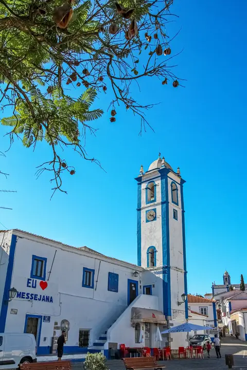 Torre sineira azul e branca e edifício caiado com o letreiro "Eu amo Messejana", em Messejana.