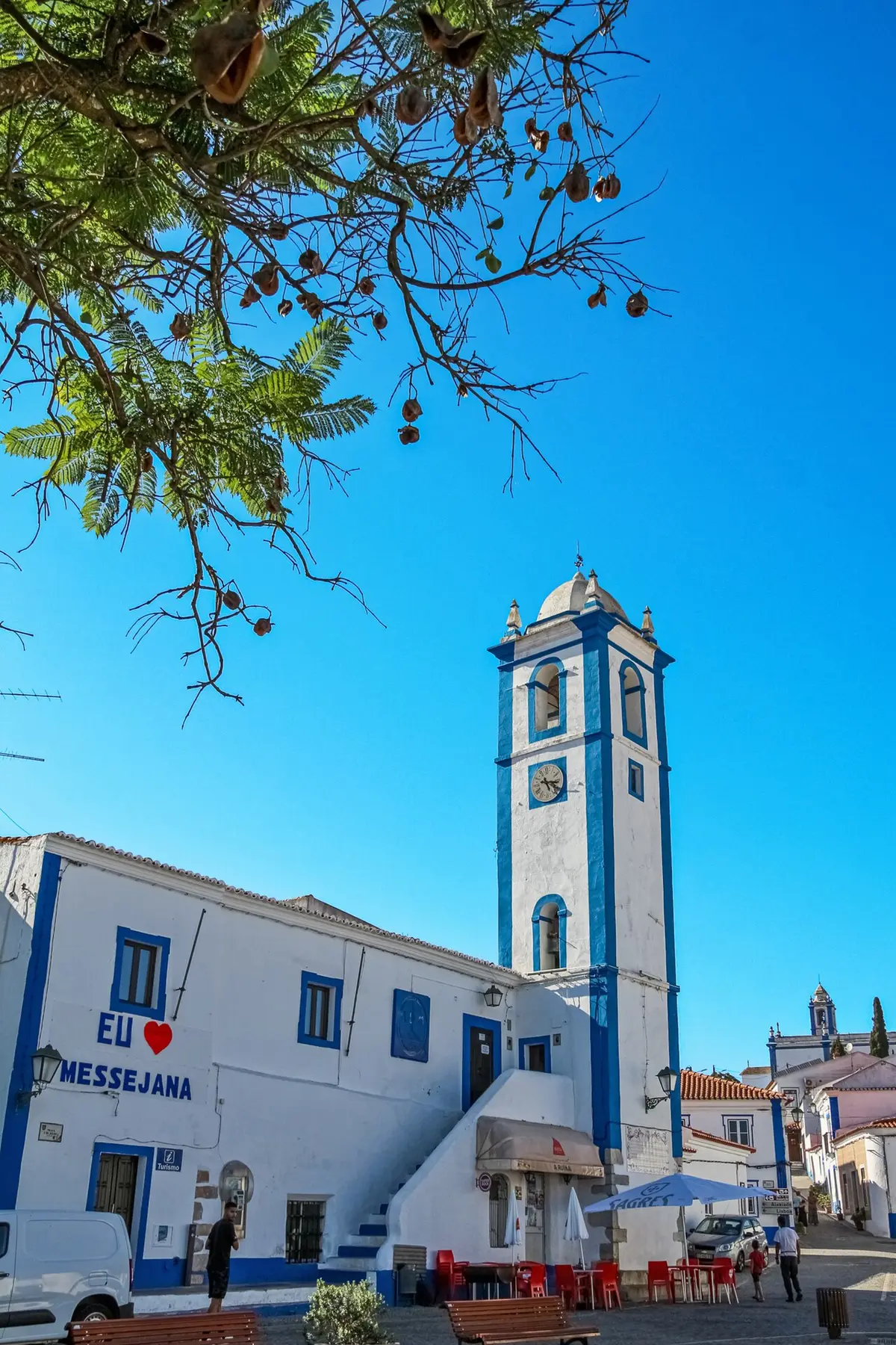 Torre sineira azul e branca e edifício caiado com o letreiro "Eu amo Messejana", em Messejana.