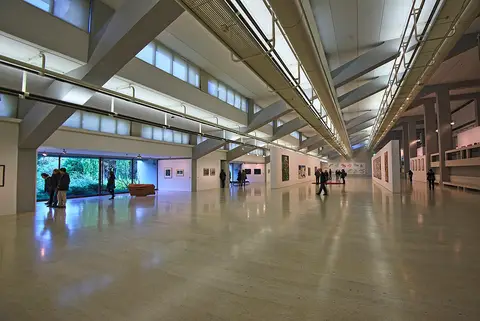 Grande sala de exposições do Centro de Arte Moderna Gulbenkian, com obras nas paredes e visitantes ao fundo