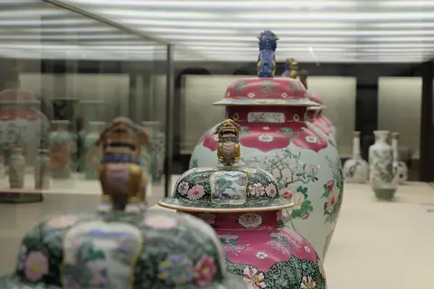 Potes de porcelana chinesa decorados com flores e leões, expostos em vitrina do museu