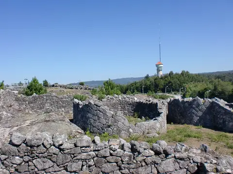 Ruínas de muros de pedra da Citânia de Santa Luzia, com torre e vigia ao fundo