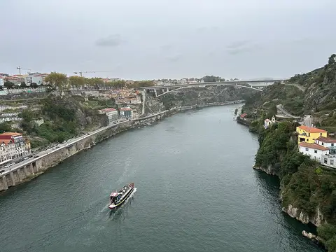 Vista do rio Douro a partir da Ponte Luís I, com barco turístico e a Ponte do Infante ao fundo