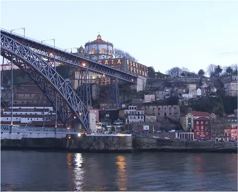 Ponte Luís I ao anoitecer sobre o rio Douro, com Vila Nova de Gaia e o Mosteiro da Serra do Pilar ao fundo