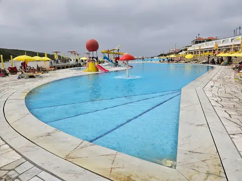 Piscina oceânica com chapéus-de-sol amarelos e estruturas de água coloridas na Praia das Maçãs