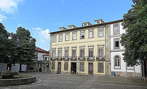 Edifício histórico da Biblioteca Municipal Raul Brandão, com fachada amarela, junto a praça com fonte
