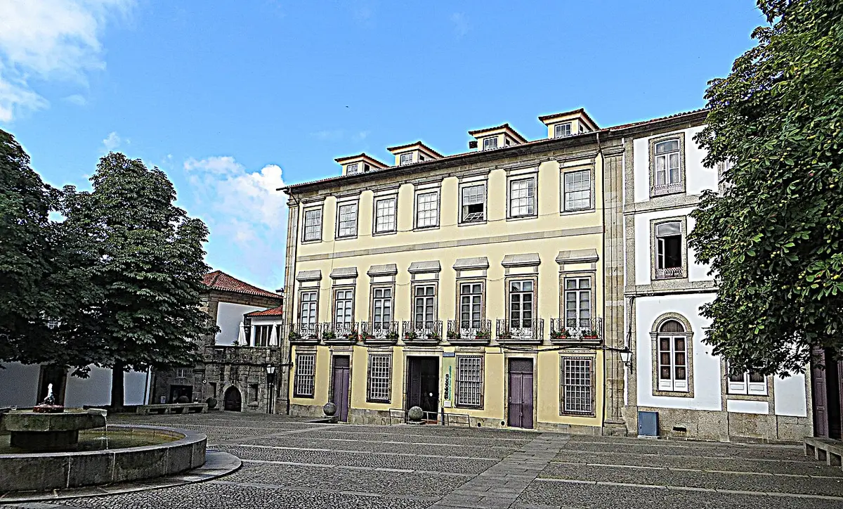 Edifício histórico da Biblioteca Municipal Raul Brandão, com fachada amarela, junto a praça com fonte