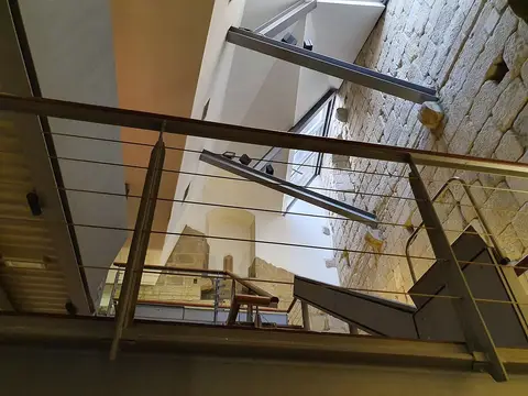 Interior da Casa do Infante com escadas modernas, corrimões metálicos e paredes de pedra