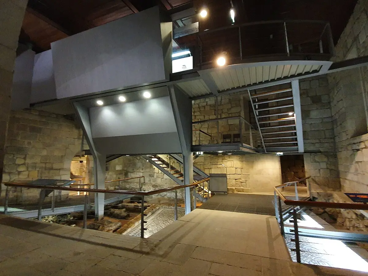 Interior da Casa do Infante com passadiços metálicos, escadaria e vestígios arqueológicos musealizados