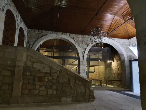 Interior em pedra da Casa do Infante, com arcos, escadaria e tecto de madeira