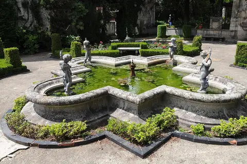 Lago ornamental com esculturas de querubins e sebes no jardim do Museu Nogueira da Silva
