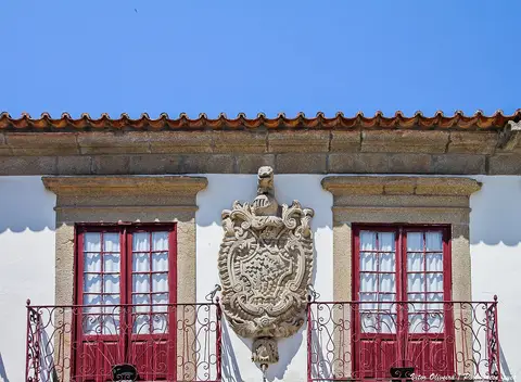 Fachada do Museu Municipal da Póvoa de Varzim com brasão de pedra entre janelas de caixilharia vermelha