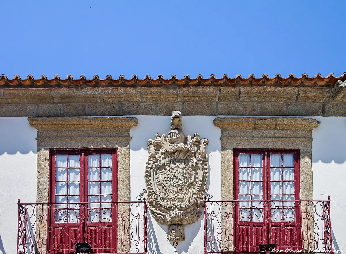 Fachada do Museu Municipal da Póvoa de Varzim com brasão de pedra entre janelas de caixilharia vermelha
