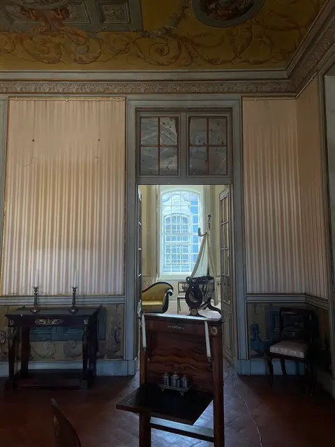 Sala histórica com tetos pintados, mobiliário de época e porta que dá para outra divisão com janela