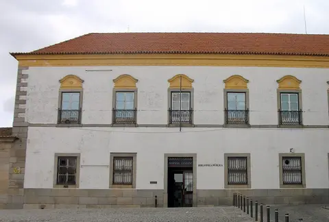 Fachada branca e amarela da Biblioteca Pública de Évora, com varandas de ferro e entrada principal