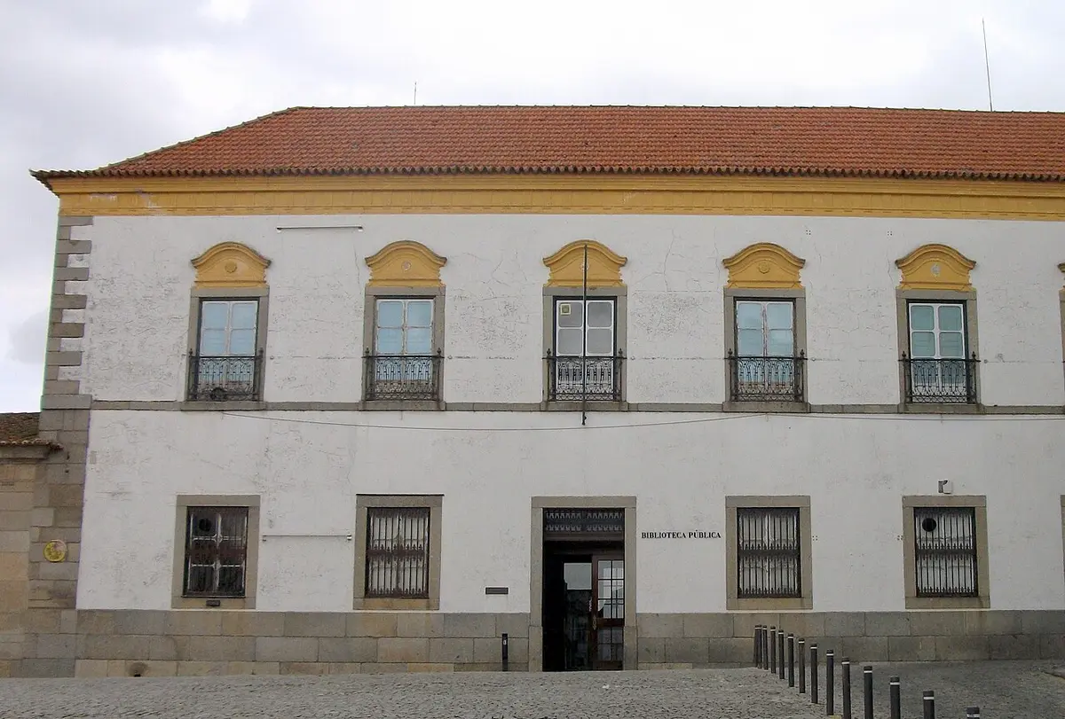 Fachada branca e amarela da Biblioteca Pública de Évora, com varandas de ferro e entrada principal