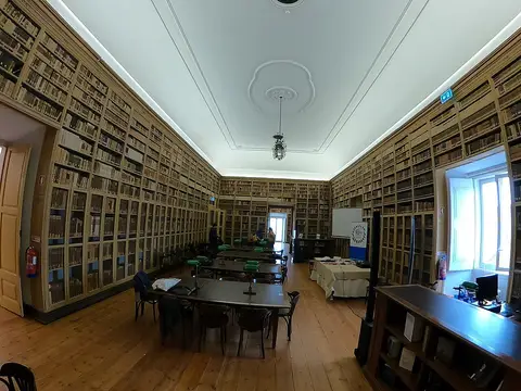 Sala de leitura da Biblioteca Pública de Évora com estantes de madeira até ao teto e mesas de estudo