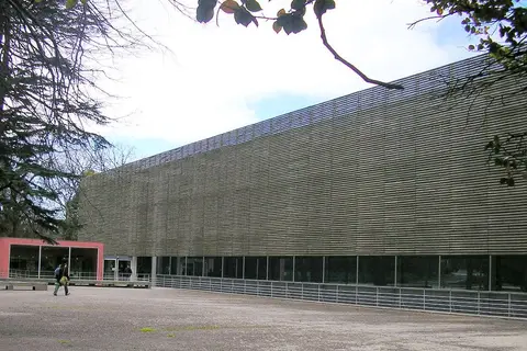 Fachada moderna da Biblioteca Almeida Garrett, no Porto, vista do exterior entre árvores.