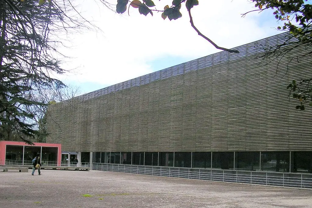 Fachada moderna da Biblioteca Almeida Garrett, no Porto, vista do exterior entre árvores.