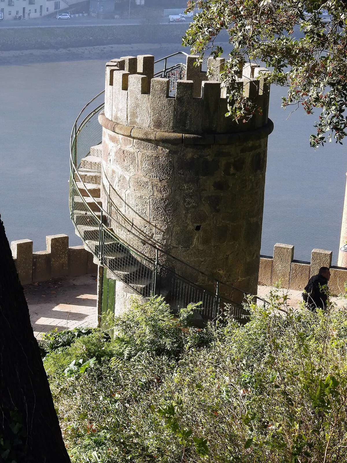Torre de pedra ameada com escada em caracol junto ao rio, num miradouro rodeado de vegetação