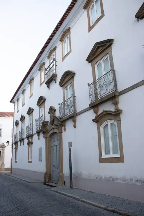 Fachada branca do Museu Municipal de Portalegre com varandas de ferro forjado e portal em pedra