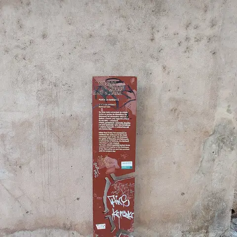 Placa informativa do Núcleo da Cidade Muralhada sobre a Porta da Barbacã, junto a parede de pedra.