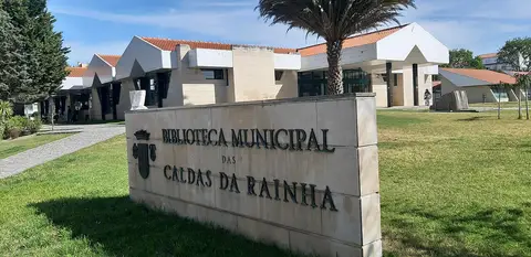Letreiro em pedra da Biblioteca Municipal das Caldas da Rainha, com o edifício e jardim ao fundo