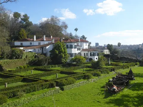 Casa Tait, no Porto, vista dos jardins com sebes recortadas e casa branca de telhado vermelho
