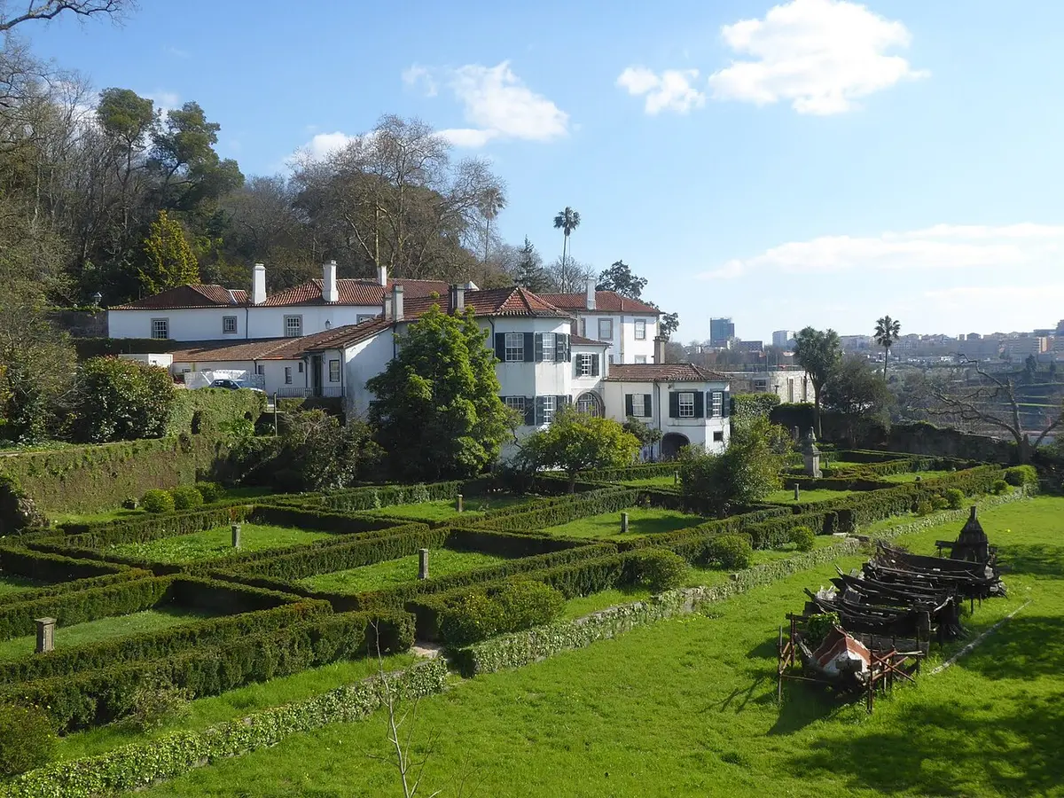 Casa Tait, no Porto, vista dos jardins com sebes recortadas e casa branca de telhado vermelho