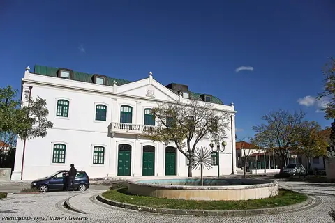 Edifício branco da Biblioteca Municipal de Oliveira do Bairro com fonte circular em frente