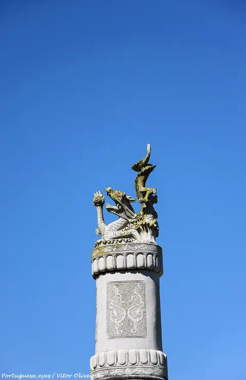 Coluna de pedra com escultura de dragão dourado no Buddha Eden, Carvalhal, sob céu azul