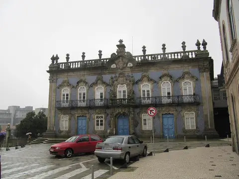 Fachada barroca do Palácio do Raio, em Braga, revestida a azulejos azuis, com carros estacionados em frente.