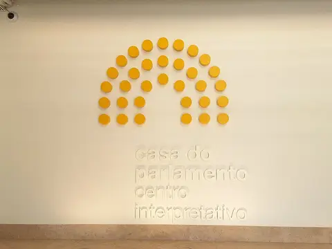 Parede de entrada da Casa do Parlamento – Centro Interpretativo com discos amarelos em hemiciclo e letreiro