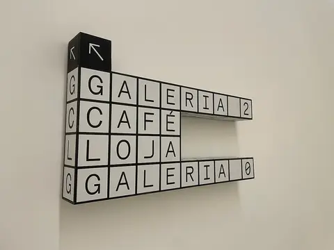 Sinalética interior em blocos a preto e branco indicando Galeria, Café e Loja