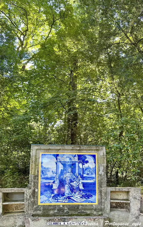Painel de azulejos azuis em muro de pedra rodeado de árvores frondosas na Mata do Fontelo, Viseu
