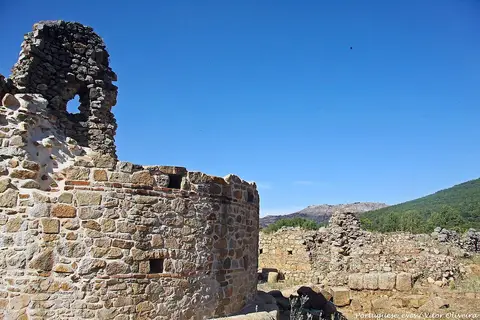 Ruínas de muros de pedra da cidade romana de Ammaia sob céu azul, com serra ao fundo